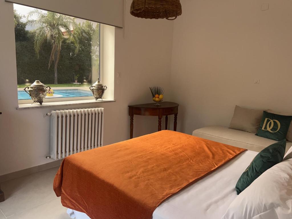 a bedroom with a bed with an orange blanket and a window at Domus Orestea Luxury Suites in Palermo