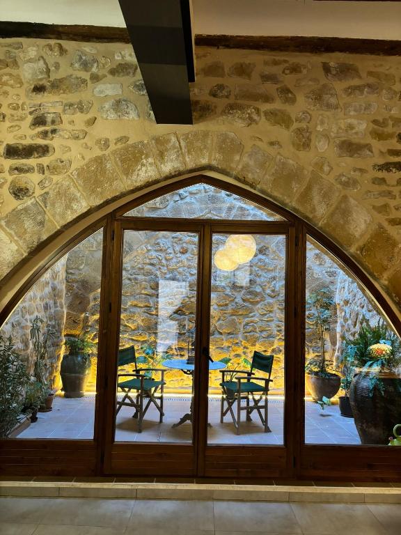 an arched window in a stone building with a table and chairs at La Fusteria d' Arnes in Arnés