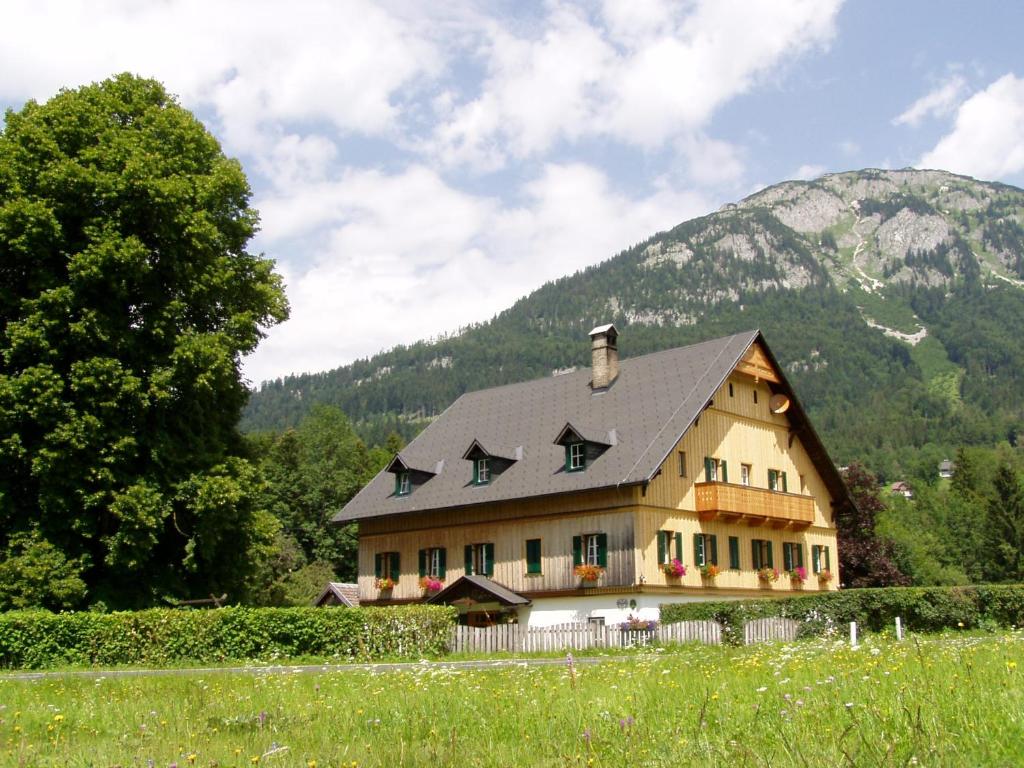 ein Haus auf einem Feld mit einem Berg im Hintergrund in der Unterkunft Die Traunmühle in Bad Aussee