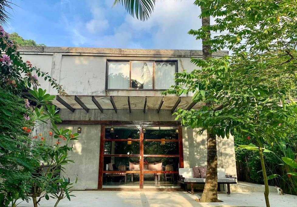 a house with glass doors in a garden at EL NIDO, Lugadia, Concrete House with Small Garden in El Nido