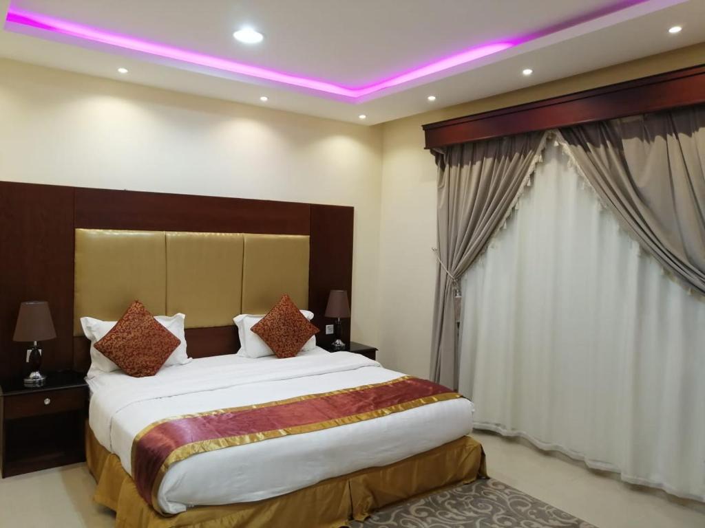 una camera con un grande letto con illuminazione viola di داركم 2 للشقق المخدومة a Buraydah