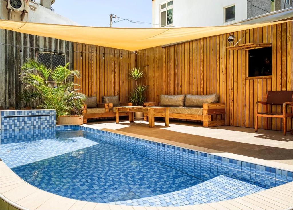 a swimming pool in a patio with a table and a couch at Slow Island Hostel in Green Island