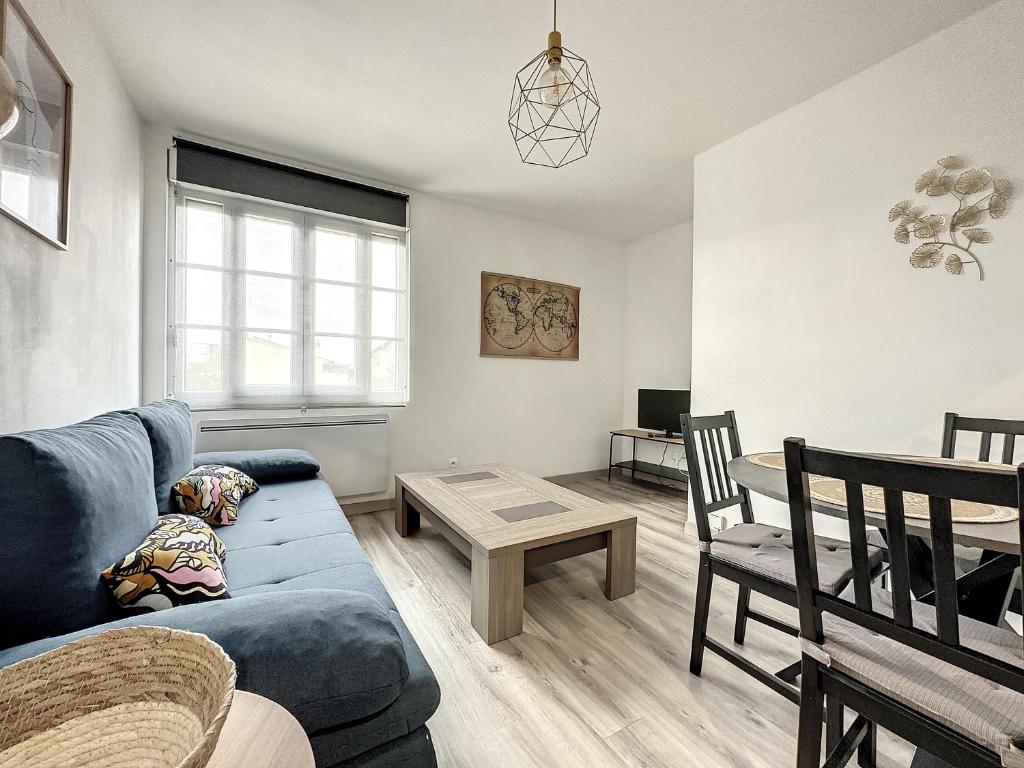 uma sala de estar com um sofá azul e uma mesa em appartement au 1er étage avec accès indépendant em Saint-Denis