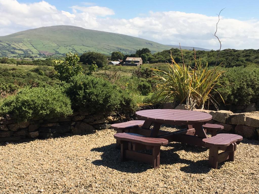 una mesa de picnic y dos bancos en un campo en Causeway Coast Country Cottage, Pet-friendly, en Ballycastle