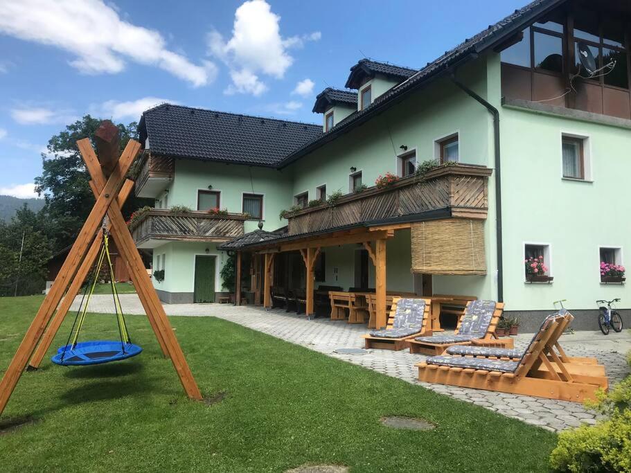 une cour avec des chaises et une balançoire en face d'une maison dans l'établissement Tourist Farm Kladje, à Ljubno