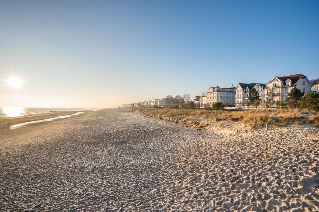 una playa de arena con casas en el fondo en Strandhotel Möwe en Bansin