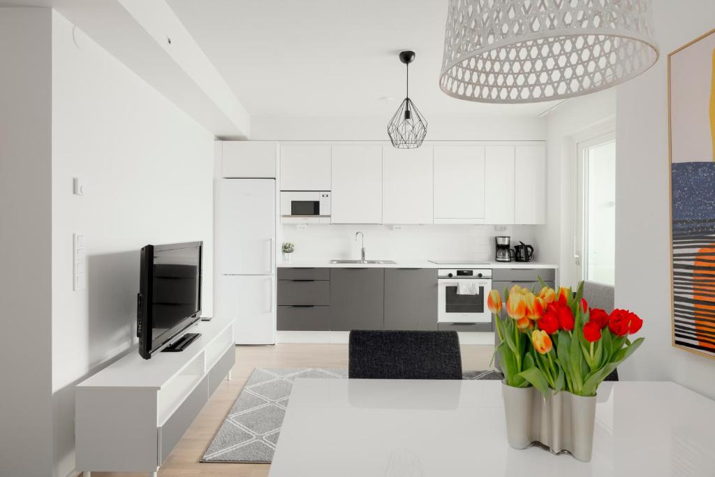 une cuisine blanche avec une table et un vase de fleurs dans l'établissement Modern LUXUS 3BR apartment Helsinki Tripla, à Helsinki