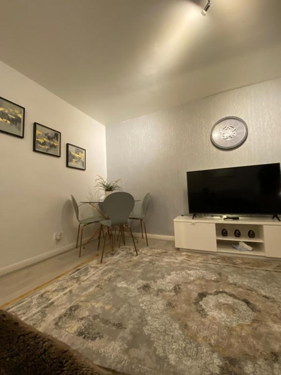 Una sala de estar con televisión, mesa y sillas. en One Bedroom Flat in Chiswick W4, en Londres