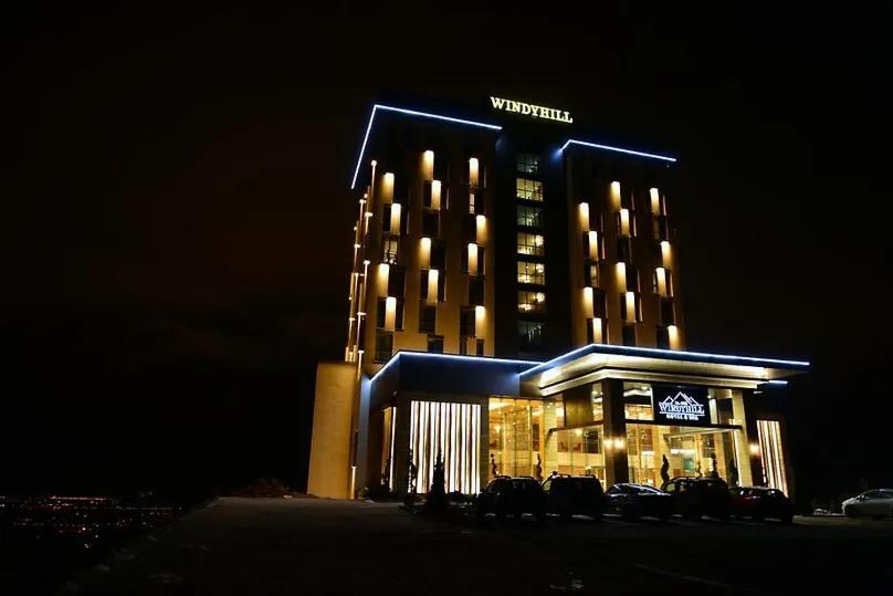 un bâtiment avec des voitures garées devant lui la nuit dans l'établissement Windyhill Hotel, à Elazığ