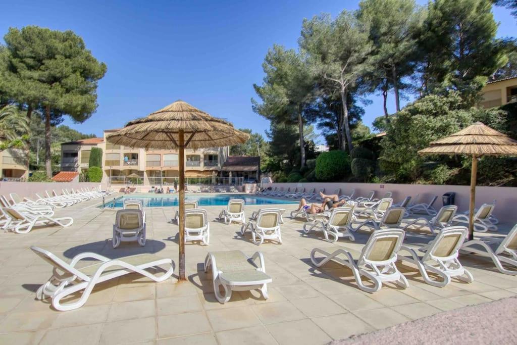 - un groupe de chaises longues et de parasols à côté de la piscine dans l'établissement Appartement piscine tennis accès privé plage Joïa, à Sanary-sur-Mer