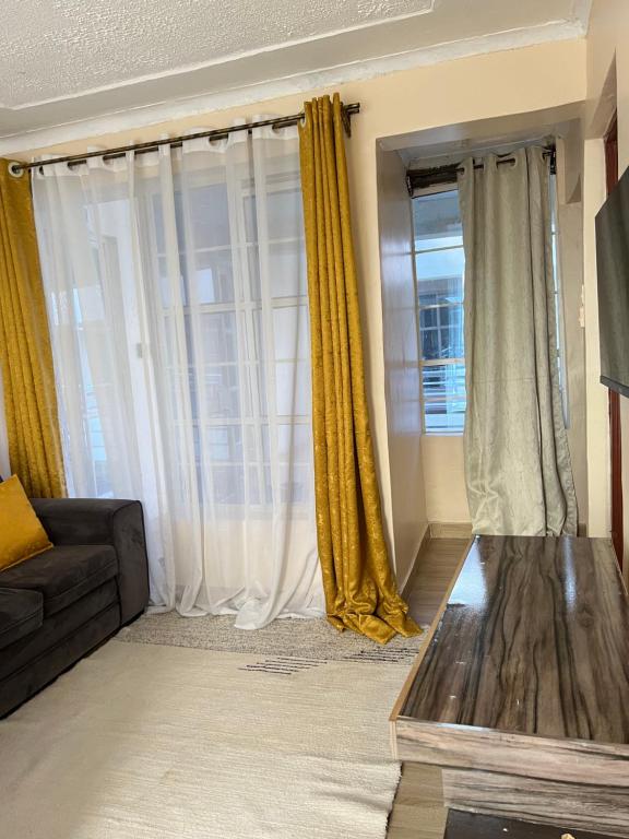 uma sala de estar com cortinas amarelas e um sofá em The comfort place Eldy em Eldoret