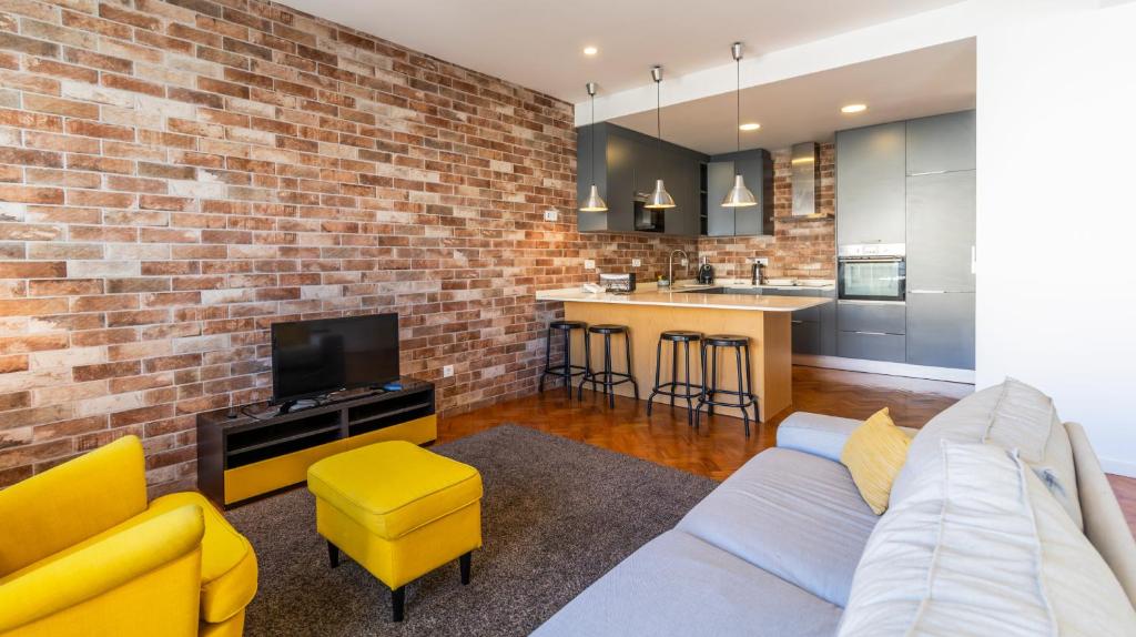 a living room with a couch and a brick wall at Charming Boavista Apartment by Unique Hosts in Porto