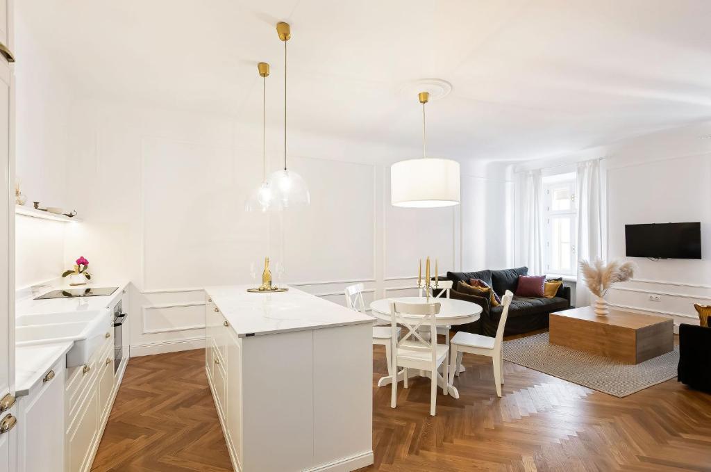 a white kitchen with a table and a living room at MARIANNA'S OLD TOWN RESIDENCE in Ljubljana