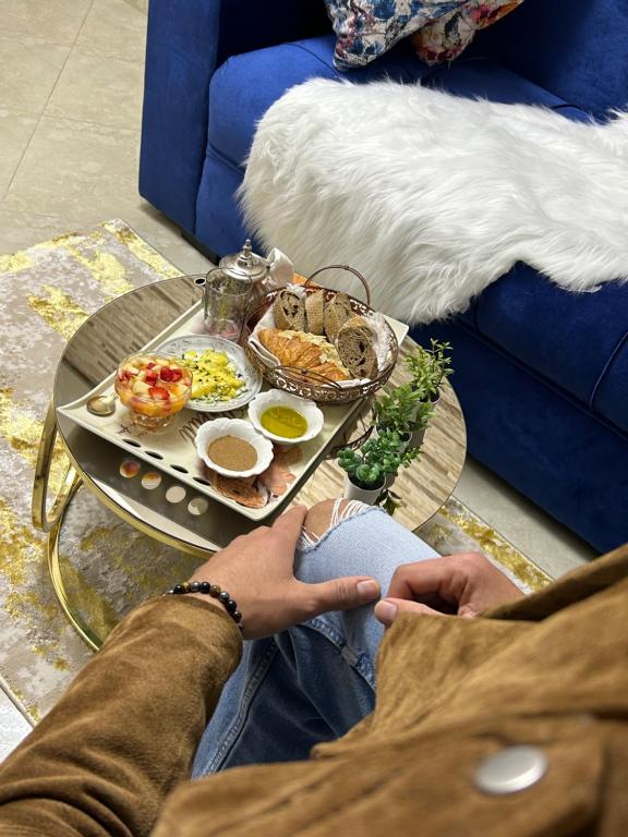um homem sentado num sofá com uma bandeja de comida em Luxury suite em Benslimane