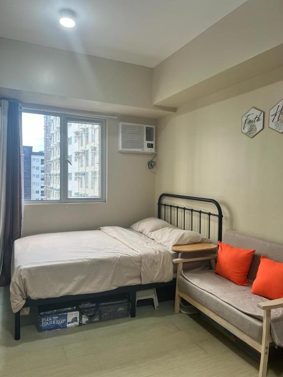a bedroom with a bed and a couch and a window at New Cute&Cozy Fully Furnished Studio - Avida Tower 2 - 100 Mbps wifi in Iloilo City