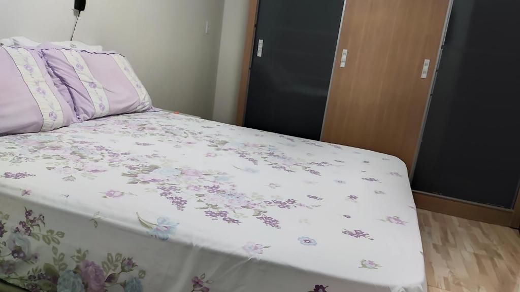 uma cama com um cobertor branco com flores em BemVyver em Indaiatuba