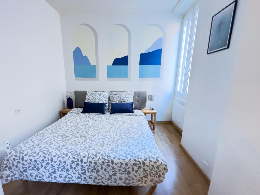 - une chambre blanche avec un lit et des oreillers bleus dans l'établissement T3 clim, TV, ART, familial, 50m du port, cuisine équipée et jeux de société, à Port-Vendres