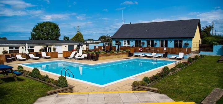 a large swimming pool with chairs and a house at Harries Lodge ocean in New Quay
