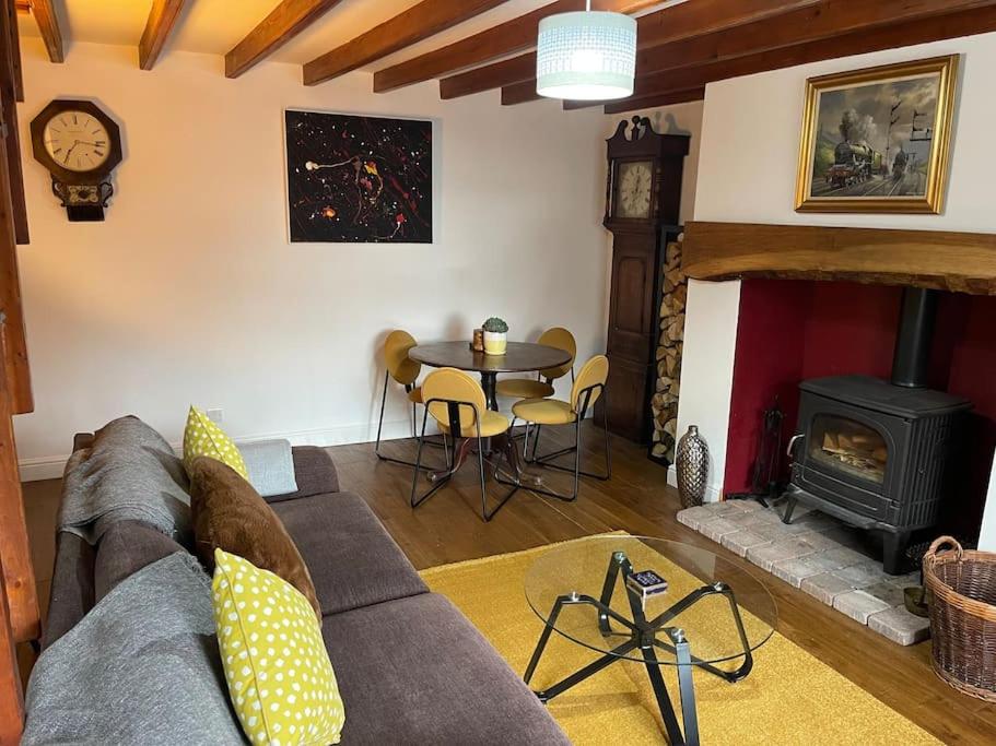 sala de estar con sofá, mesa y chimenea en Stunning Cottage with Log Burner en Frosterley
