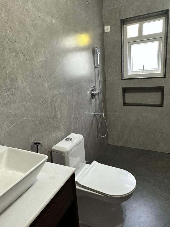 a bathroom with a white toilet and a sink at 2 bedroom beautiful shared villa with private kitchen and parking in Siolim