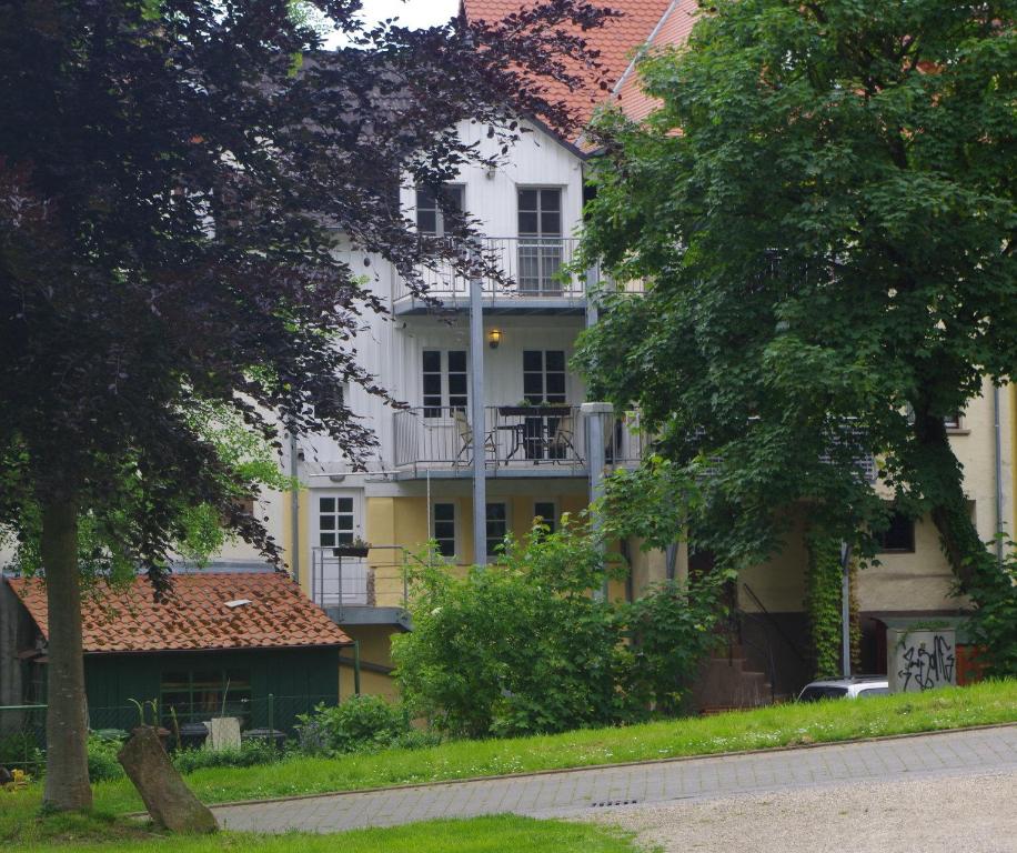 a large white building with a balcony and trees at Ferien-Wohnung am Menzer-Park in Neckargemünd