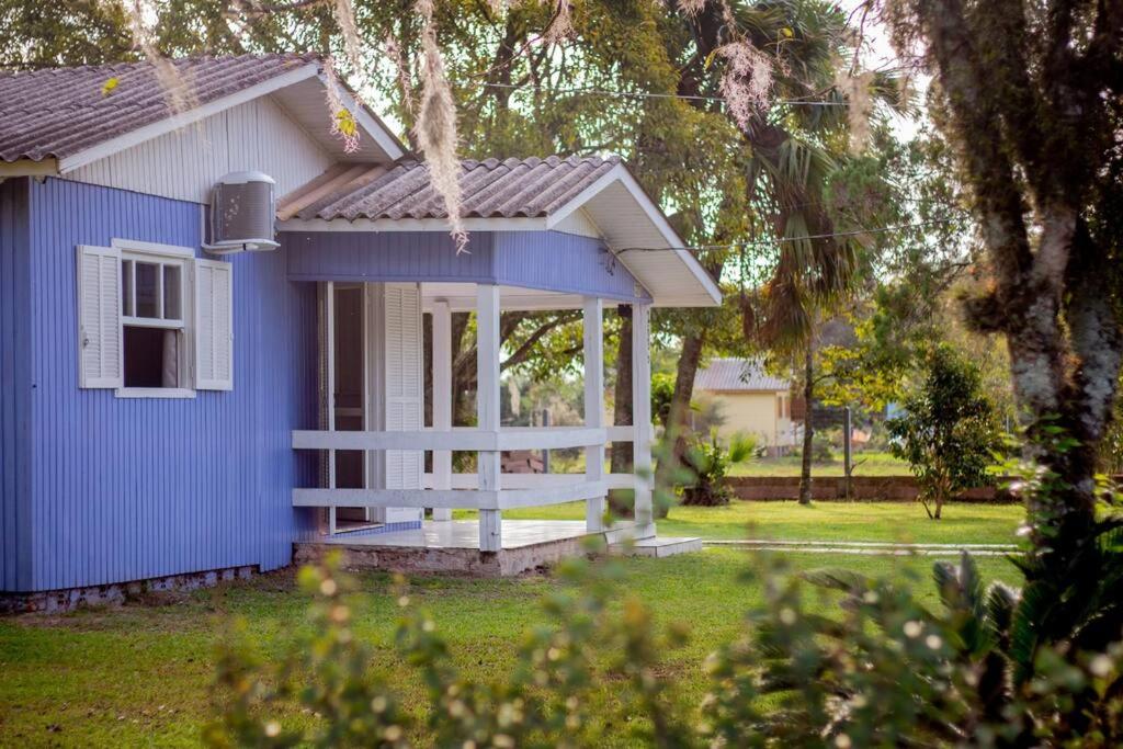 een blauw-wit huis met een veranda bij Casa d campo, pátio amplo, cercado. 5min do centro in Rolante