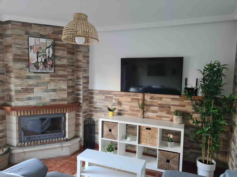 a living room with a fireplace and a flat screen tv at La Casuca de Trasmiera en Arnuero in Arnuero