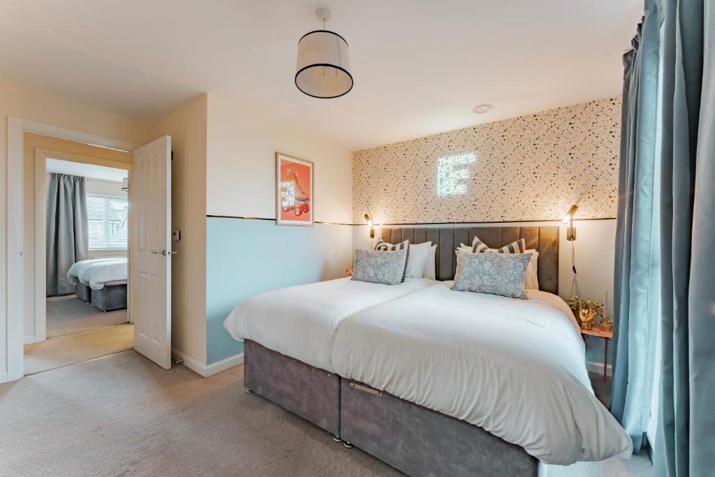 1 dormitorio con 1 cama blanca grande con almohadas azules en Stylish & Spacious 3bed Home with Fast Wifi & Private Parking, en Cambourne