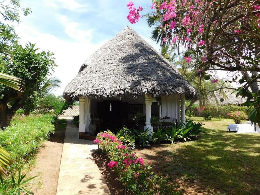 a small hut with a thatched roof and flowers at Holiday home in Malindi in Mambrui