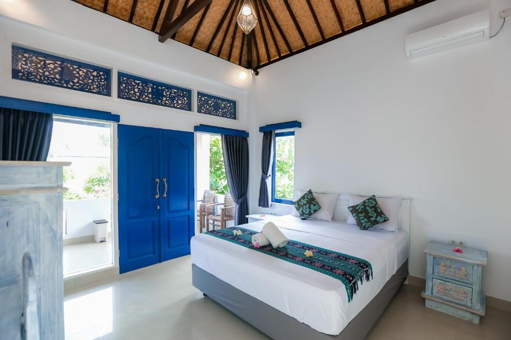 Cozy Bungalows في غيلي تراوانغان: غرفة نوم بسرير وابواب ونوافذ زرقاء