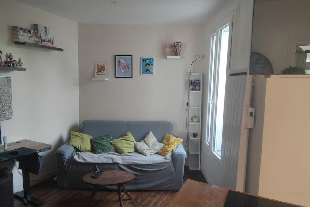 - un salon avec un canapé bleu et des oreillers dans l'établissement Studio 2 pièce charmant et calme, à Boulogne-Billancourt