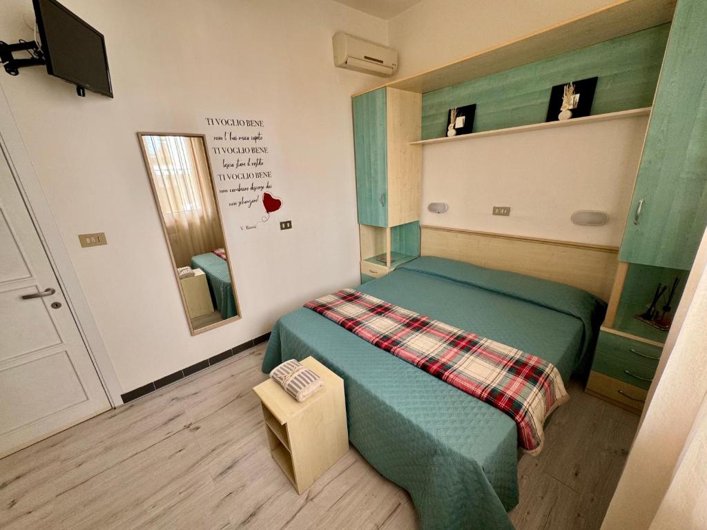 um pequeno quarto com uma cama verde e um espelho em Bilocale al mare em Rimini