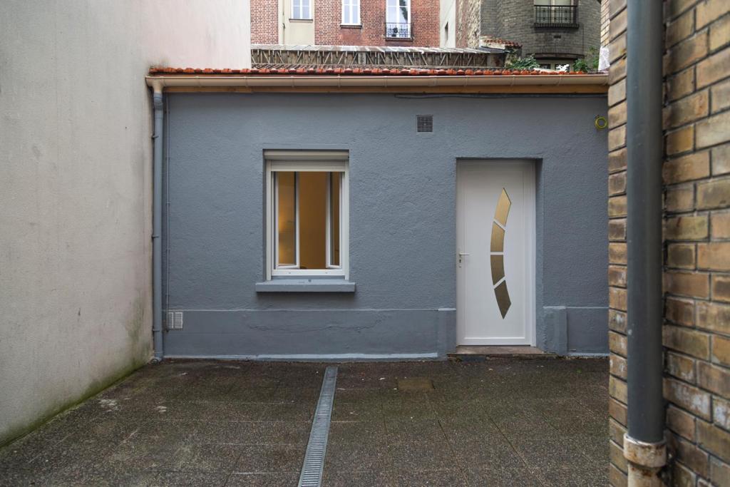 ein blaues Gebäude mit einer weißen Tür und einem Fenster in der Unterkunft Maisonnette à Clichy in Clichy