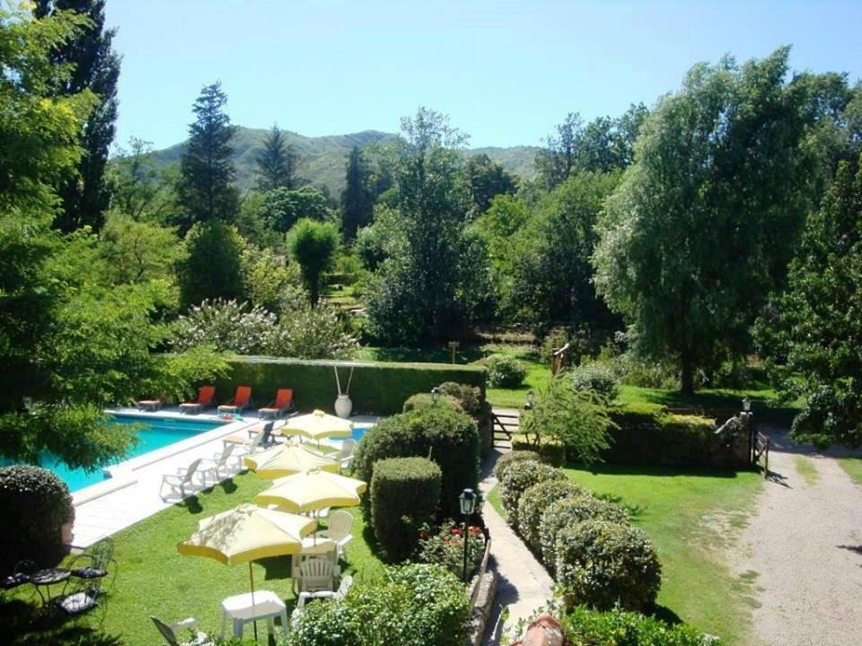 a garden with a swimming pool and umbrellas at Aldea Kleinwald in Villa General Belgrano