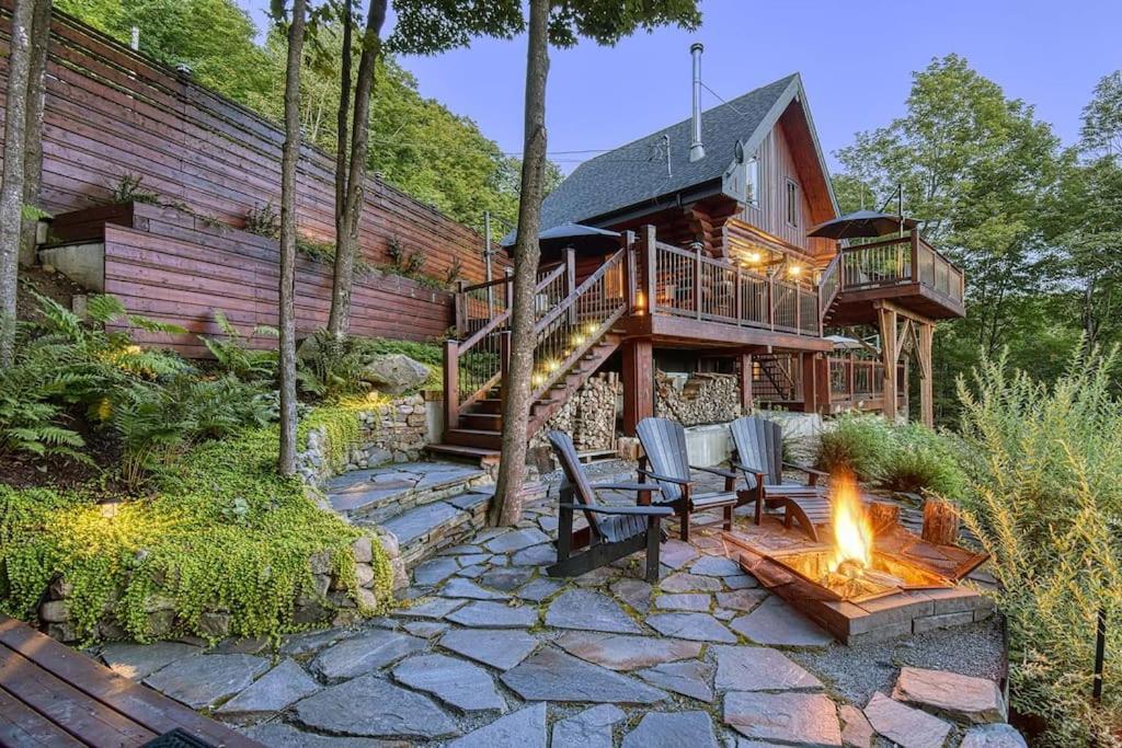 una casa con una hoguera delante de ella en Luxurious log cabin with private spa, en Lac-Supérieur