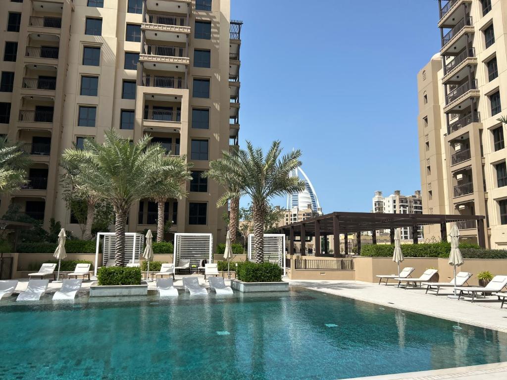 a swimming pool with chaise lounges and chairs and buildings at StoneTree - Luxury 1BR - Best Location for Tourist in Dubai