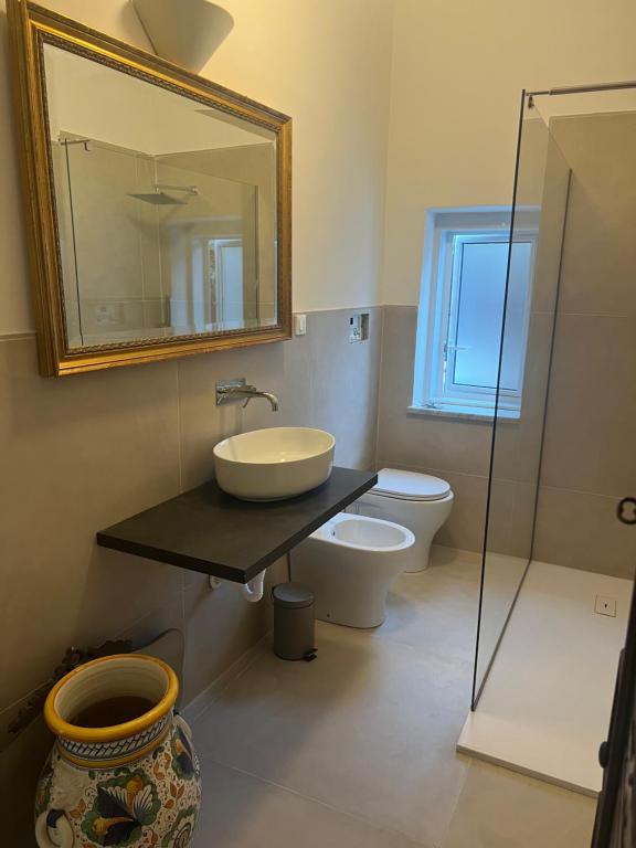a bathroom with a sink and a toilet and a mirror at Domus Orestea Luxury Suites in Palermo