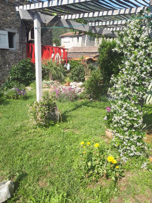 un jardin avec une pergola et des fleurs dans une cour dans l'établissement maison typique cévenole avec jardin, à Mialet