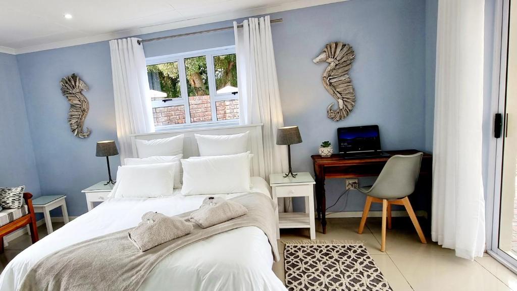 a bedroom with a bed and a desk with a computer at Cozy Island Living at The Grove cottage in Knysna