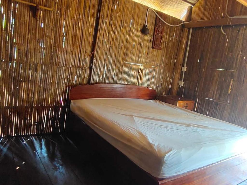 Cama en habitación con pared de madera en Odambang Village Homestay, en Battambang