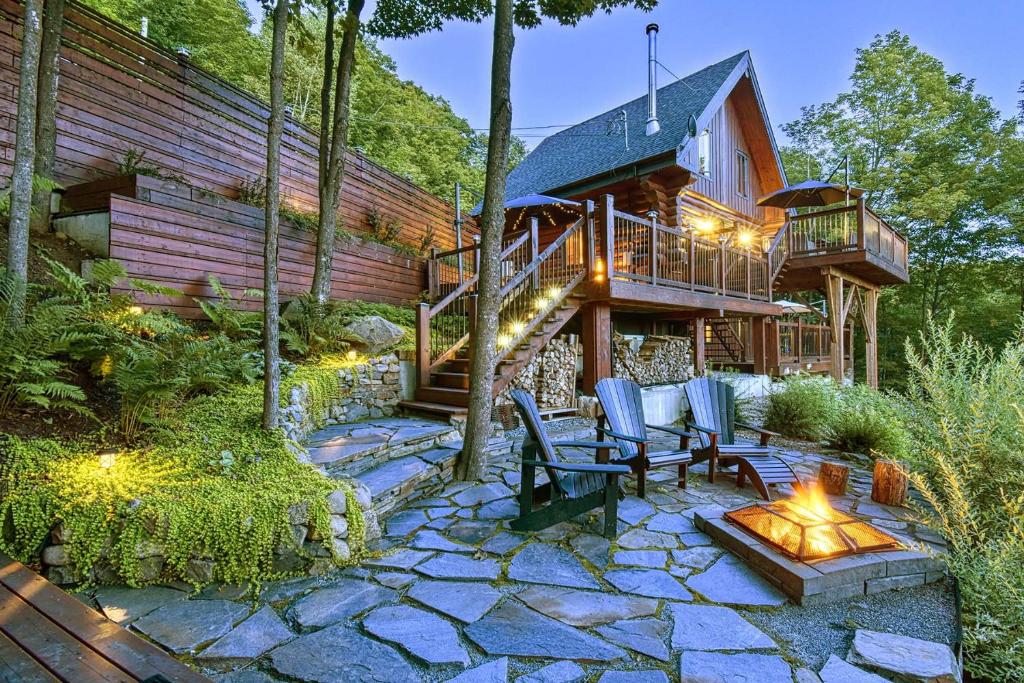 uma casa de madeira com um pátio e um deque em Luxurious log cabin with private spa em Lac-Superieur