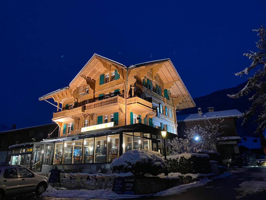 um grande edifício à noite na neve em Post Hotel Vista em Zweisimmen