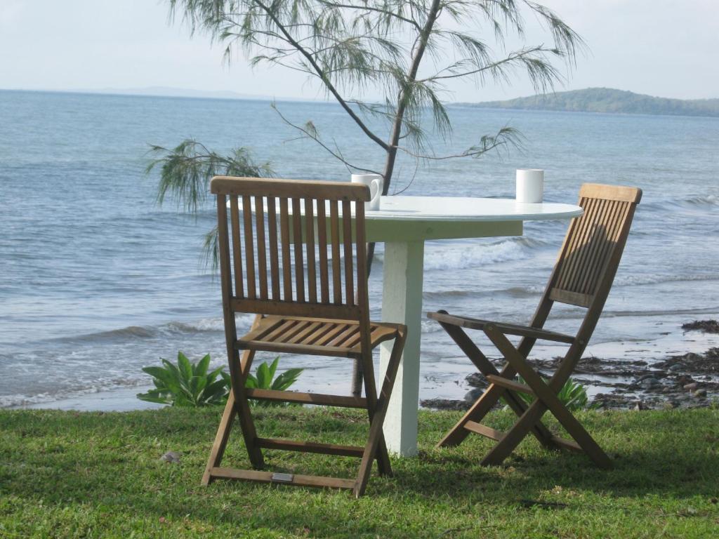 - une table et deux chaises installées à côté de l'océan dans l'établissement Campwin Beach House, à Sarina