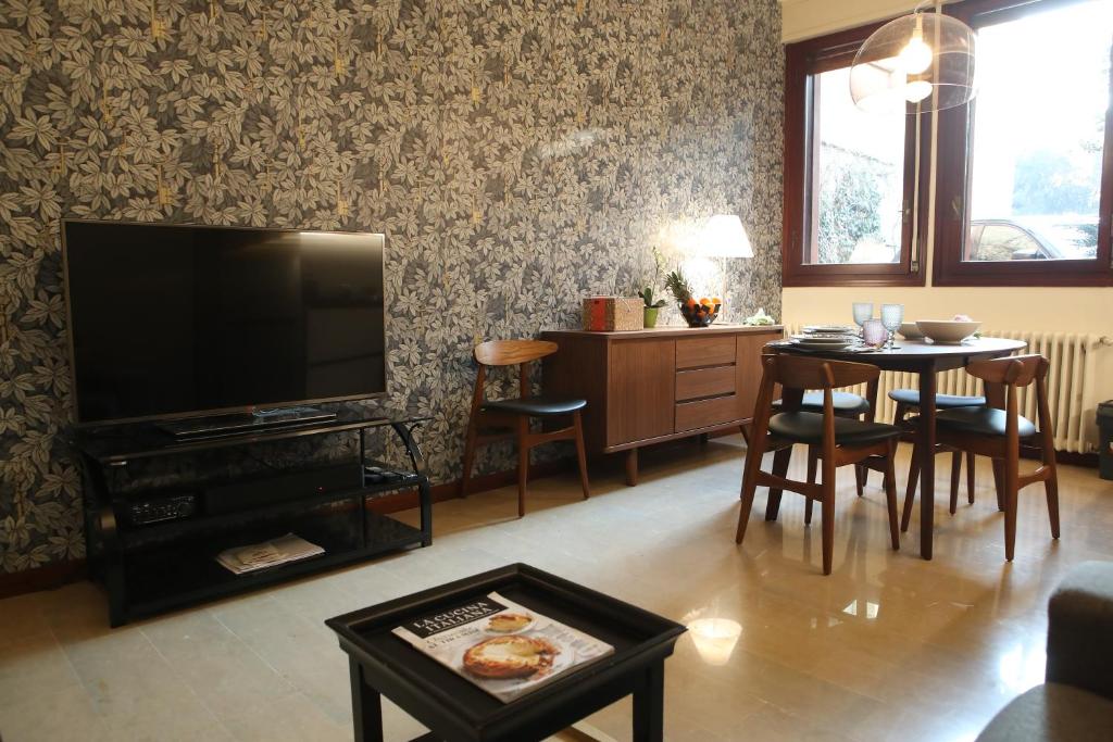 uma sala de estar com televisão e uma mesa com cadeiras em Casa moderna nel centro di Imola em Imola