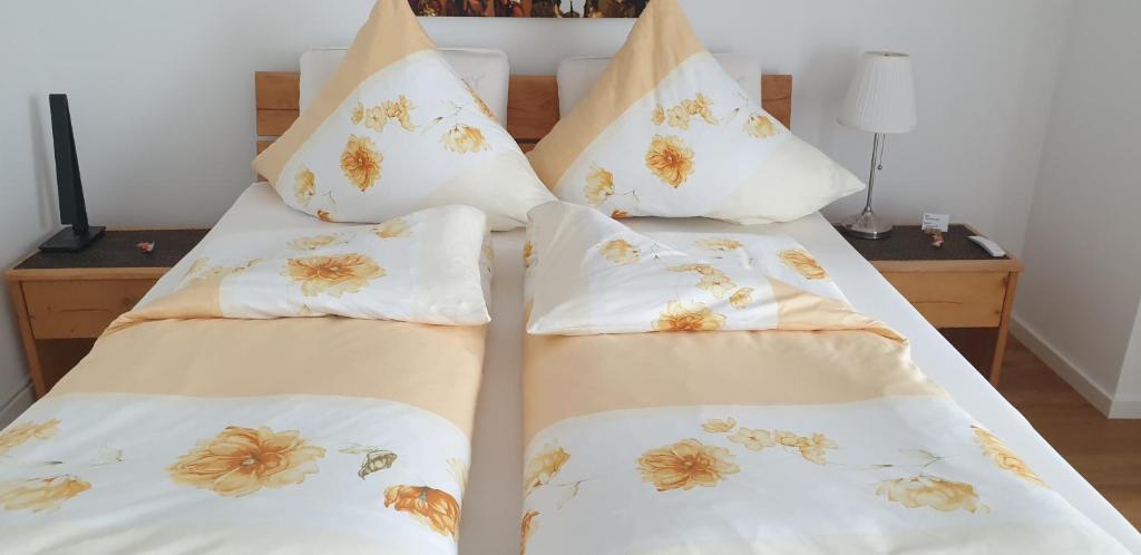 a bedroom with two beds with white sheets and floral pillows at Ferienwohnung Dreiländereck 1 in Lörrach