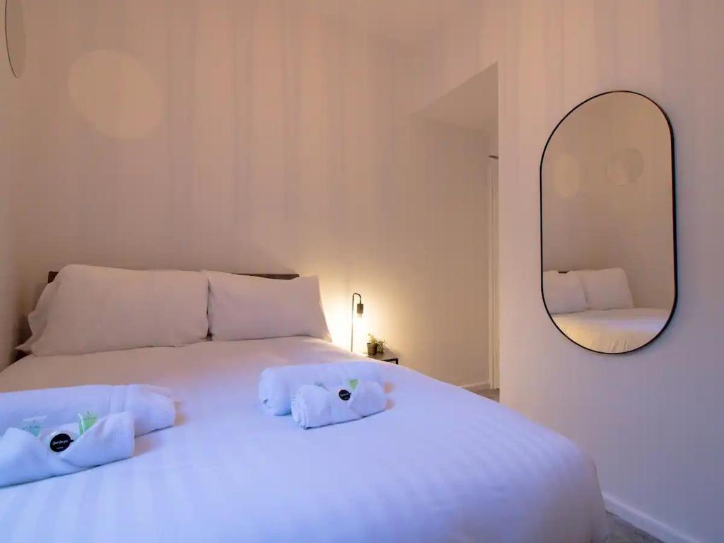 um quarto com uma cama branca e um espelho em Pass the Keys Modern Apartment in the Heart of Newcastle em Newcastle upon Tyne