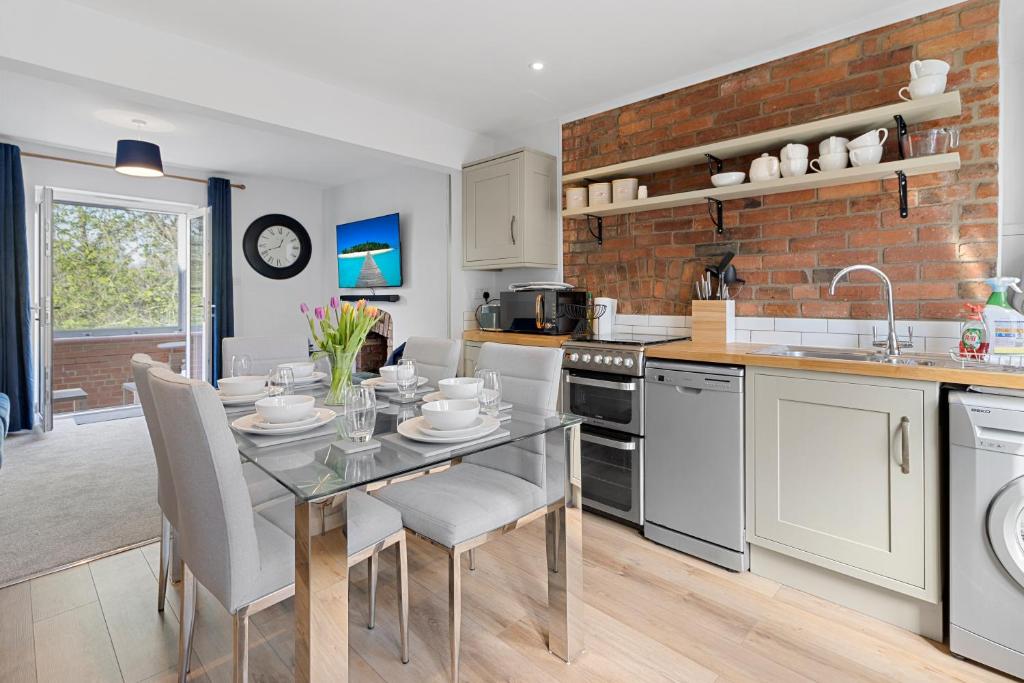 cocina con mesa de cristal y pared de ladrillo en Exe Riverside Retreat Holiday Home en Exeter