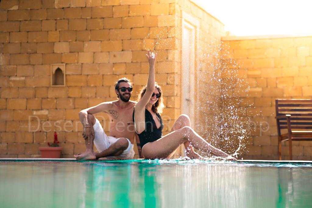 Ein Mann und eine Frau, die am Pool sitzen in der Unterkunft Desert Dream Royal Camp with Pool in Jaisalmer