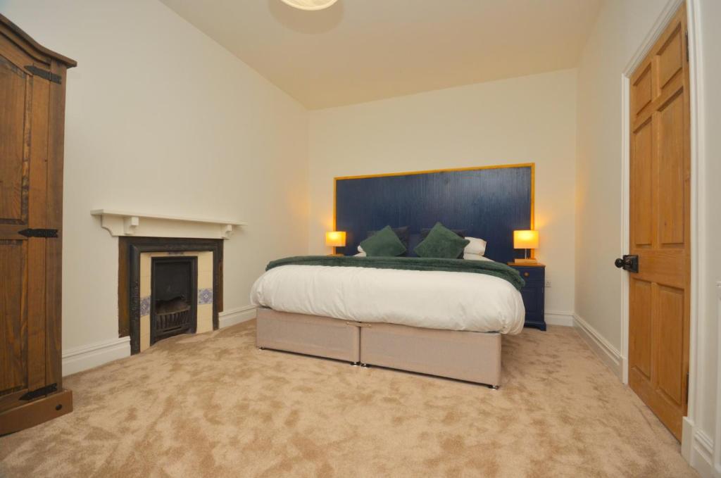 a bedroom with a large bed and a fireplace at The Gate Lodge in Helensburgh