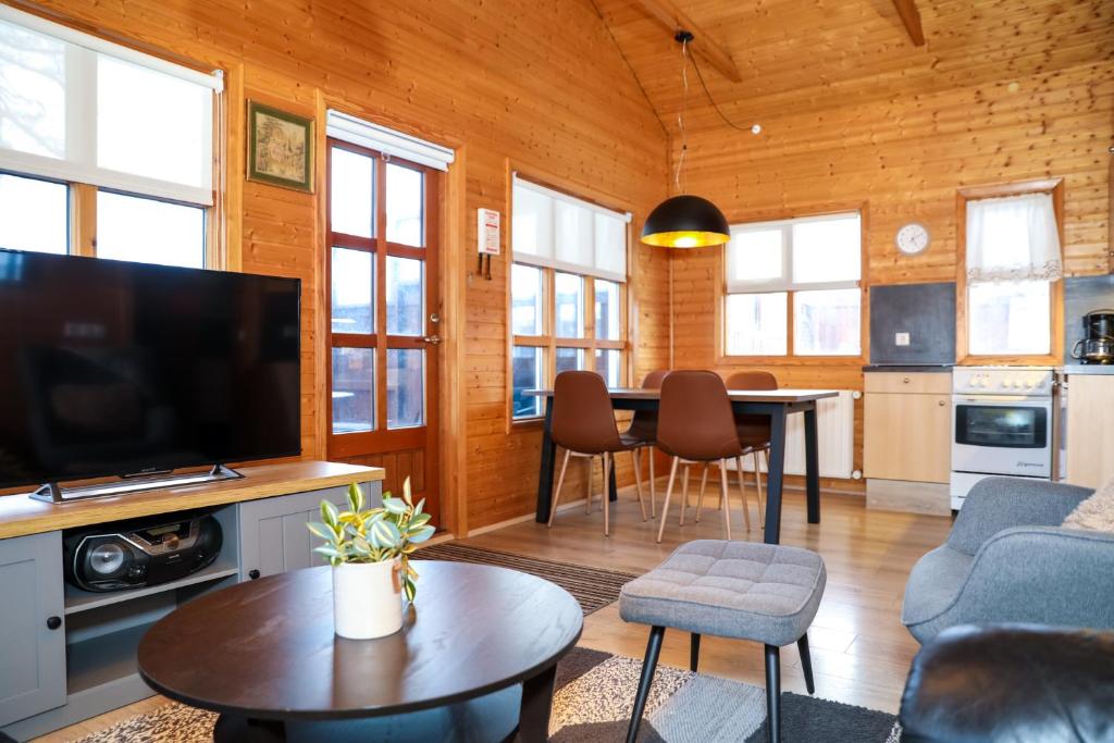 a living room with a television and a table with chairs at Akureyri Cottages in Akureyri